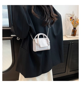 Close-up of white mini square bag with crocodile texture and silver chain strap
