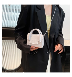 Close-up of white croc-embossed mini crossbody bag with silver chain on model