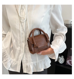 Detail of dark brown crocodile embossed mini crossbody bag with silver chain strap