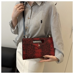 Detailansicht der roten Handtasche mit Schlangenmuster, Griff und Metalllogo