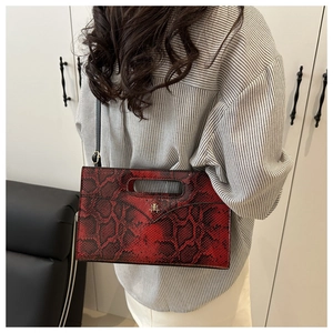 Detail der rot-schwarzen Schlangenleder-Optik Handtasche mit goldenem Logo auf dem Korpus