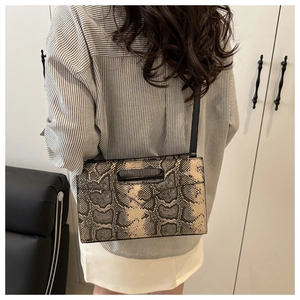 Schicke Umschlagtasche mit Schlangenmuster und schwarzem Schultergurt zum Streifenhemd