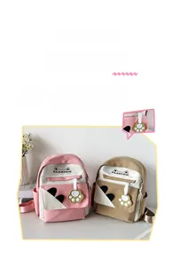 Close-up of cute canvas backpacks in pink and khaki with cat ear designs and paw charms