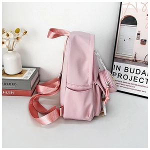 Vista laterale dello zaino in nylon rosa con spallacci regolabili e piccolo borsellino tondo