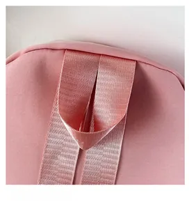 Detail of pink nylon shoulder bag featuring a reinforced woven top handle and stitch texture