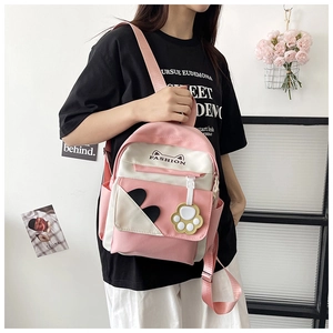 Pink and white cat-themed backpack with paw pendant shown from side view on model
