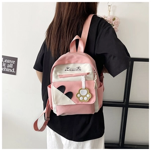 Detail of pink and white school backpack with cute cat ear pattern and paw charm