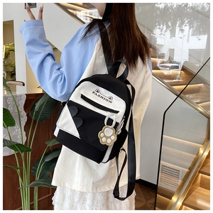 Detail of a black and white cat-ear backpack with FASHION print and yellow paw charm