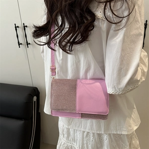 Chic pink crossbody flap bag with glossy panel worn by a model in a modern room