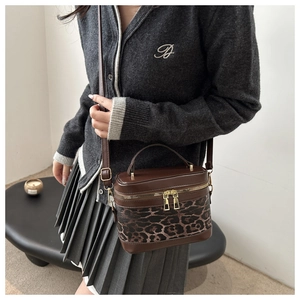 Détail du sac seau à imprimé léopard avec garniture en cuir brun et zip doré