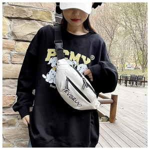 Outdoor shot of a white nylon crossbody bag with black straps on a black sweatshirt