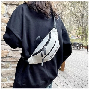 Detail showing white crossbody bag with black zipper and adjustable strap in outdoor use