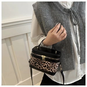 Détail du sac seau léopard avec fermetures éclair dorées et bandoulière en cuir