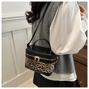 Nahaufnahme der Box-Tasche mit Leopardenmuster und goldenen Reißverschlüssen am Model
