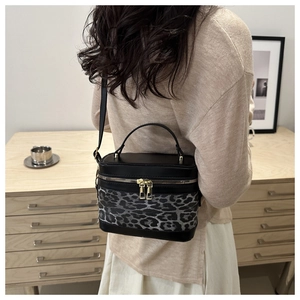 Detail view of leopard print crossbody bag with gold zippers and black leather strap