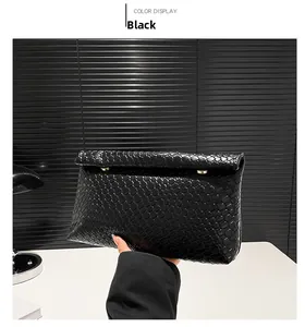 Detail of black woven leather clutch with gold metal clasp and cross-weave texture