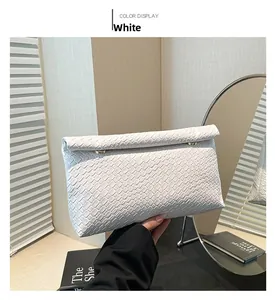 Detail of white woven PU leather clutch bag with elegant gold metal magnetic buckle