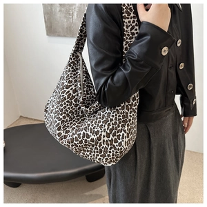 Close-up of leopard print canvas tote bag styled with a black leather jacket on model