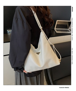 Detail of white leather tote with metallic triangle logo and spacious soft structure
