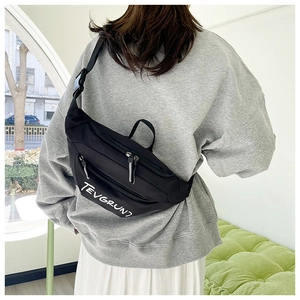 Close-up of black nylon crossbody bag with white letter printing and adjustable strap