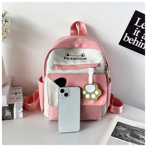 Detail of pink and white canvas backpack featuring cat ear patterns and a cute paw charm