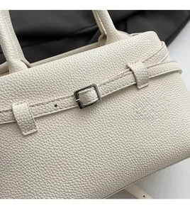 Close-up of white pebble leather texture and silver buckle detail on the handbag