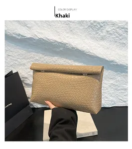 Detail of khaki PU leather envelope clutch with woven texture and crocodile pattern