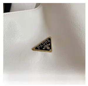 Macro shot of white textured leather material with classic triangular metal brand plaque