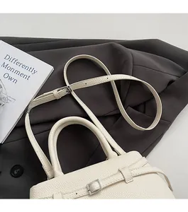 Close-up of white lychee pattern leather bucket bag with silver metal buckles and strap