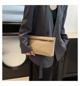 Detail of beige woven texture envelope clutch with gold buckle and leather finish
