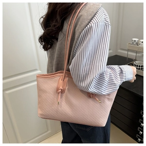 Detail showing the textured pink tote bag with fashion lettering and slim shoulder strap