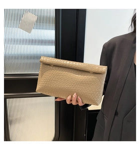 Détail de la texture tressée beige et fermeture à rabat sur cette pochette moderne