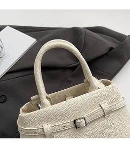 Close-up of pebble grain leather handbag showing rounded handle and metal buckle detail
