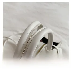 Detail of pure white handbag featuring durable dual handles and fine stitching craftsmanship