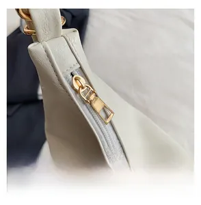 Close-up of smooth gold-tone zipper hardware on cream leather shoulder tote bag