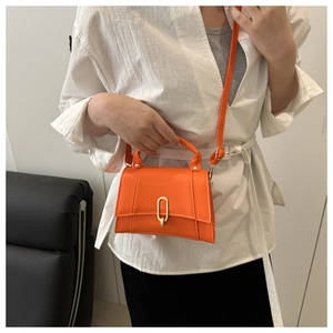 Detail der orangefarbenen Ledertasche mit goldener Schnalle und verstellbarem Schultergurt