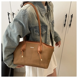 Detail of brown woven leather shoulder bag with knot detail and 'FASHION' text print
