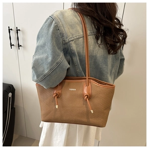 Brown woven tote bag featuring a leather patch and dual slim shoulder straps for daily wear