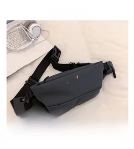 Vue détaillée du sac banane de sport gris avec sangle réglable à côté d'un ordinateur
