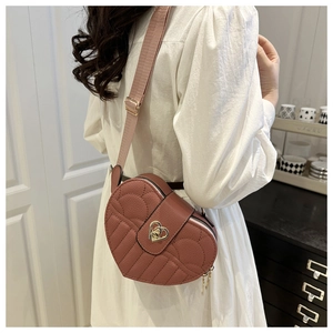 Detail of heart shaped crossbody bag with quilted texture and metal heart twist lock