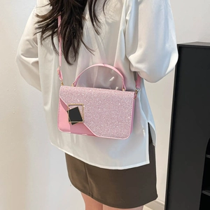 Sac à bandoulière rose pailleté avec boucle dorée porté par un mannequin pour le style