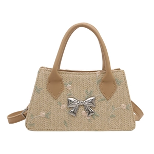 Fashionable straw square handbag with floral embroidery and bow detail on white background
