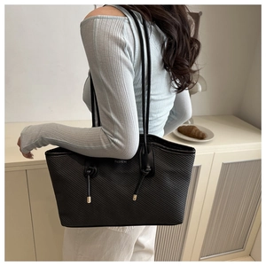 Detail of black tote bag with diagonal quilted texture and silver FASHION logo