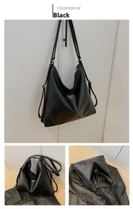 Detail of black leather tote showing the metal triangle logo and smooth zipper closure