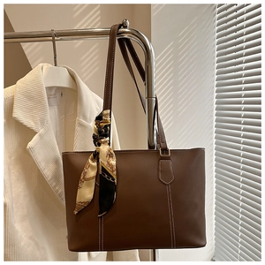 Detail of dark brown tote bag with white stitching and retro chain pattern silk scarf