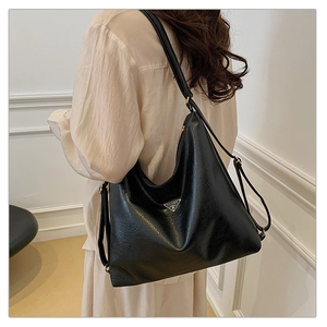 Detailed view of the large black tote bag featuring a triangle metal logo and PU texture