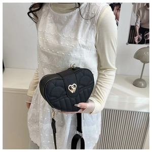 Detail of black heart-shaped quilted bag with gold rotating heart lock and textured leather