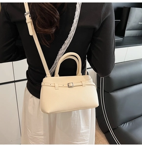 Detail of off-white bucket bag featuring lychee grain texture and silver buckle strap
