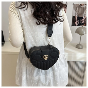 Litchi texture black heart-shaped crossbody bag with gold hardware shown on a model
