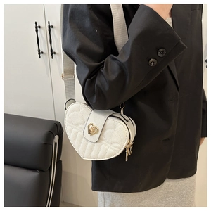 Detail of white heart crossbody bag with gold heart lock and embroidered wing pattern